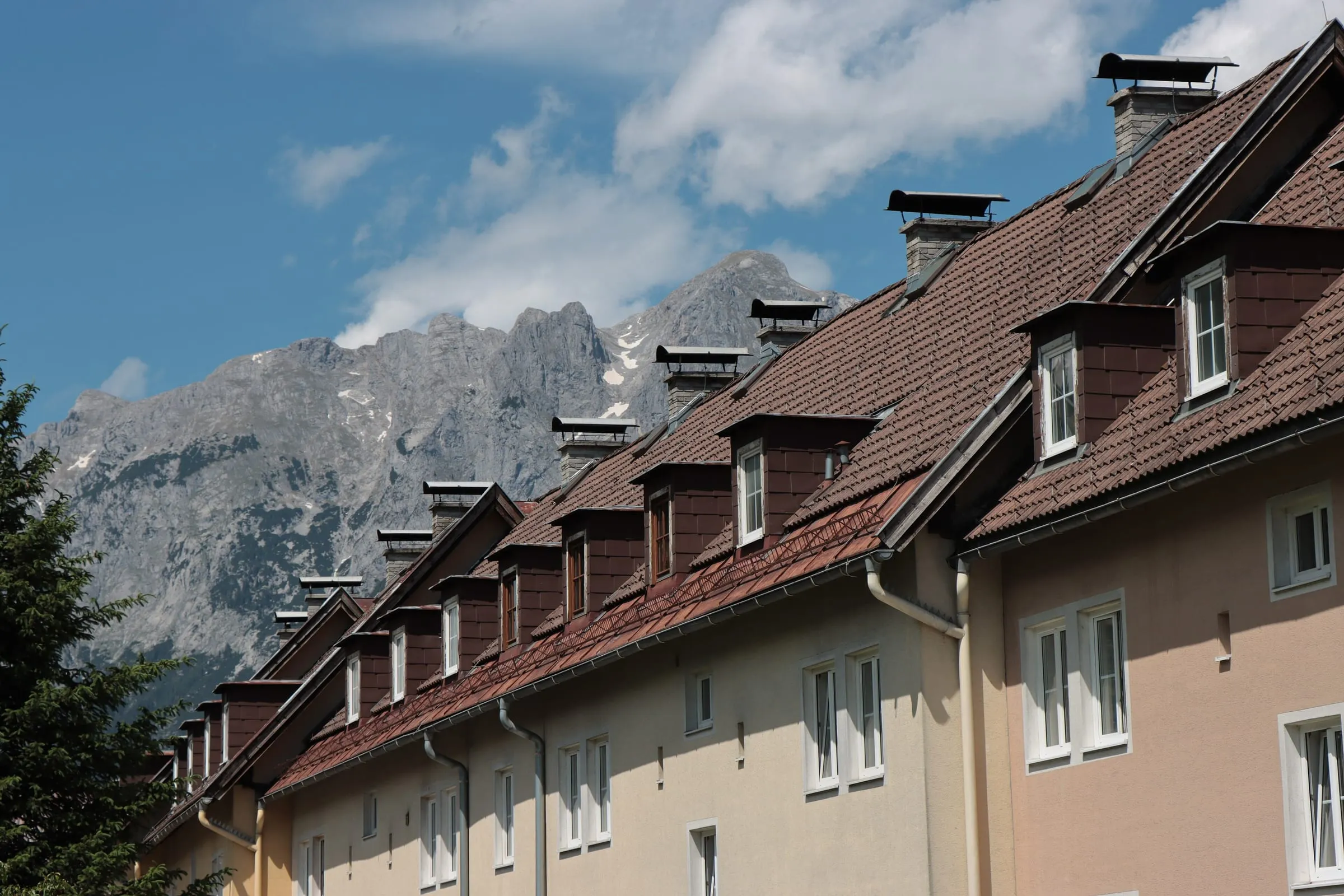 Wohnhäuser mit Gaupen in Bischofshofen vor Bergkulisse – Symbolbild