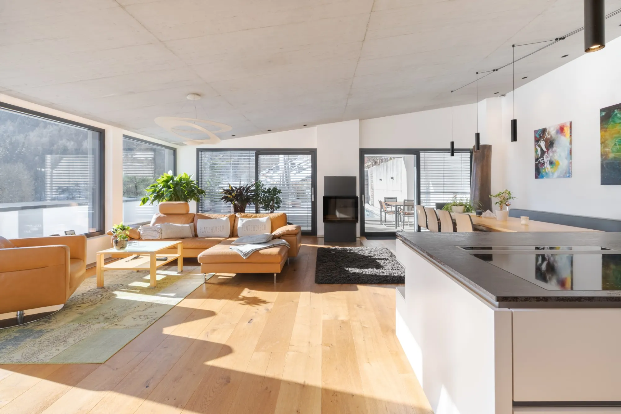 Heller Wohnbereich mit Holzboden, Sitzgruppe und offener Küche in einem Penthouse in Bischofshofen