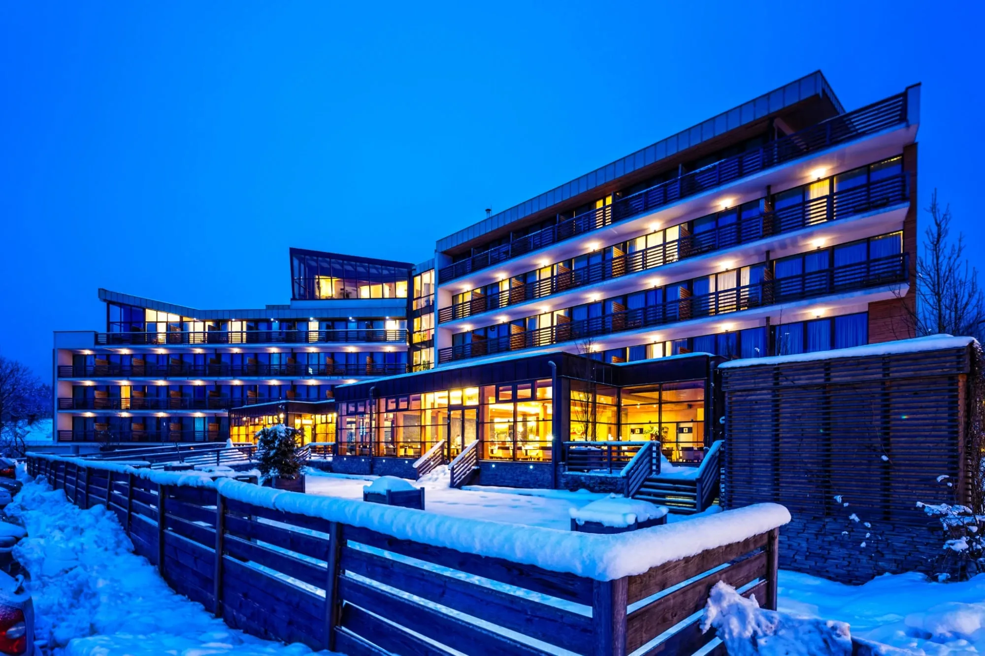Beleuchtetes Hotel mit Terrasse an einem Winterabend – Symbolbild