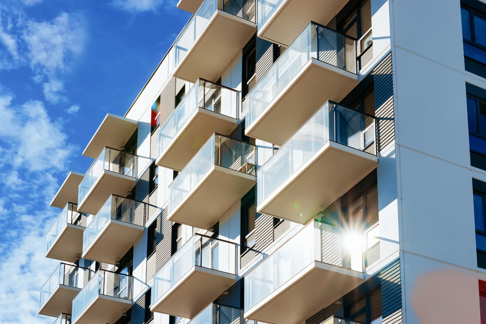 Moderne Wohnanlage mit Glasbalkonen vor blauem Himmel